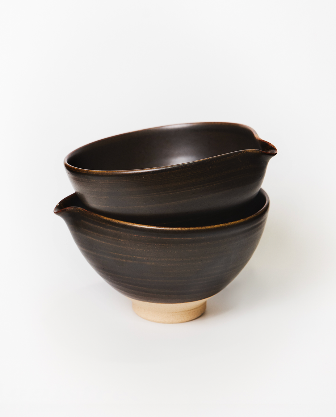 Two black ceramic bowls stacked on a white background