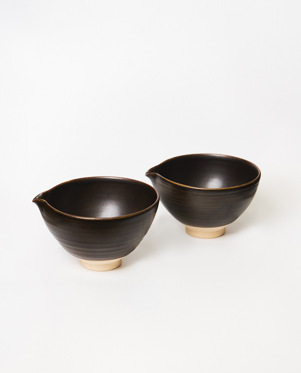 Two black ceramic bowls with beige bases on a white background