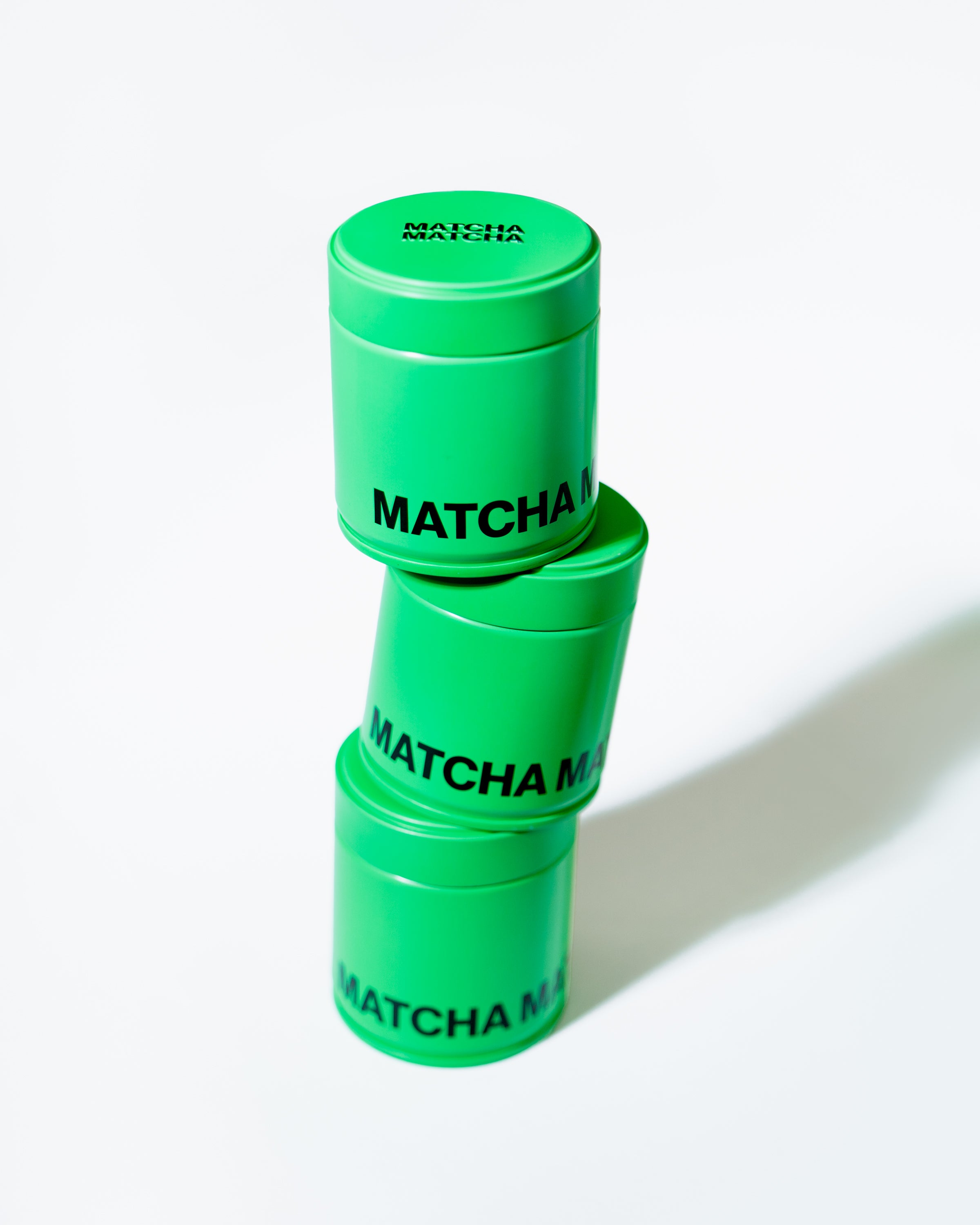 Three Matcha Matcha Cans stacked vertically, bright green tins with black logo, ceremonial grade Uji matcha powder.