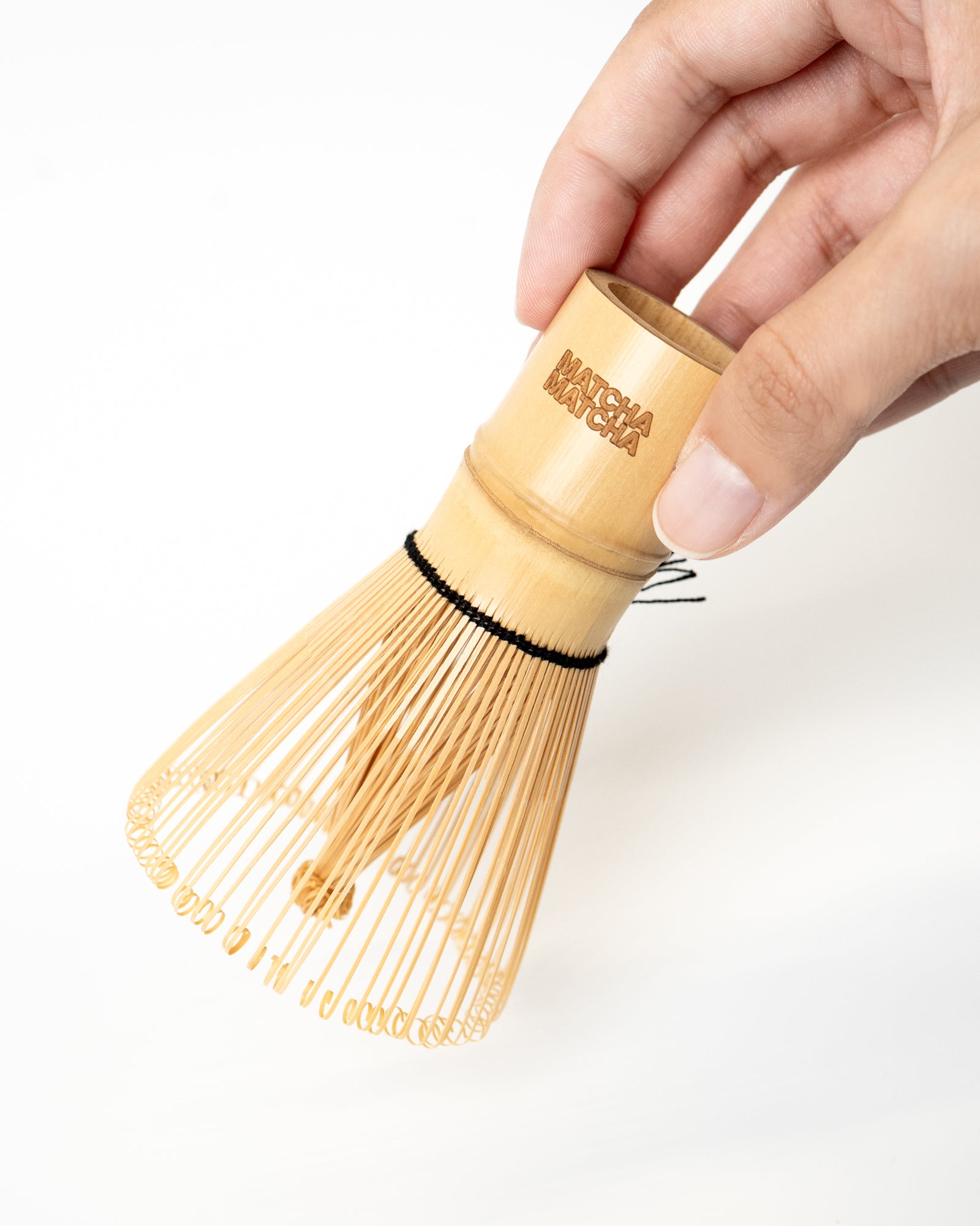 Bamboo whisk held by a hand with 'Matcha Matcha' branding